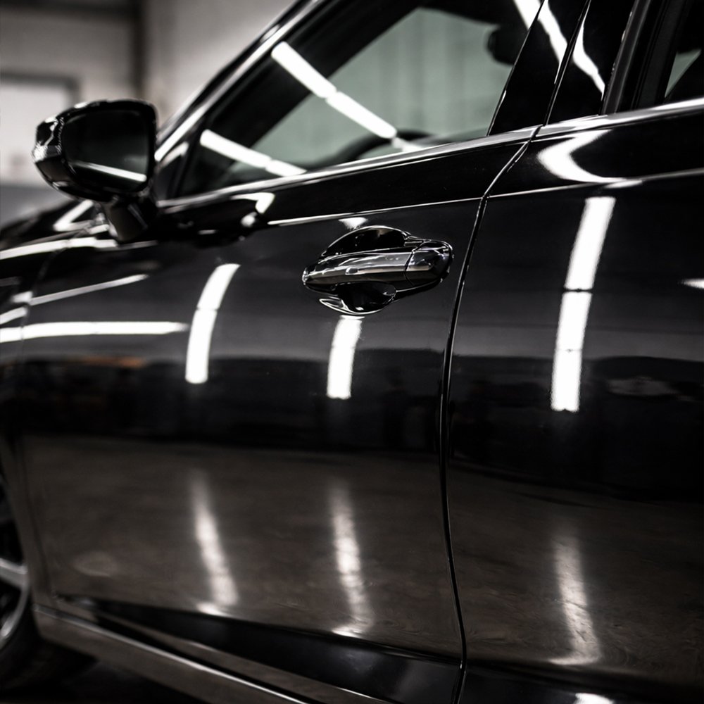 Black vehicle door panel showing flawless paint finish after spot touch-up in Toronto repair facility.